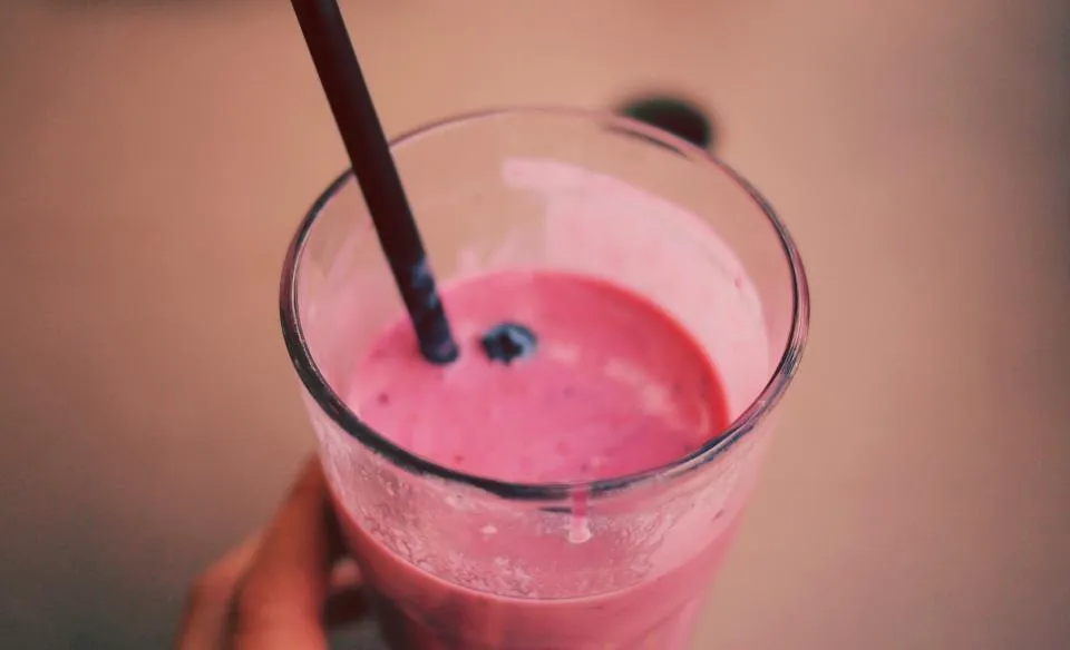 A pink berry smoothie with a straw